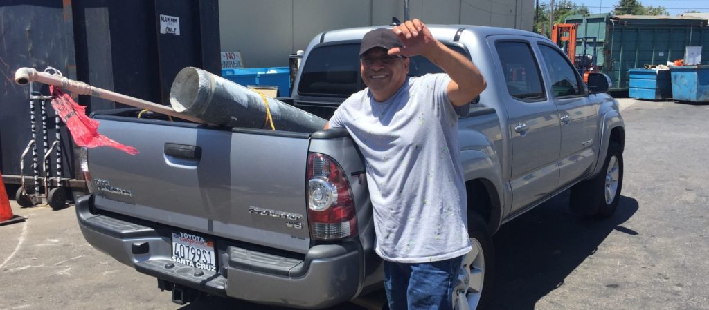 man unloads metal recycling from the back of a pickup truck